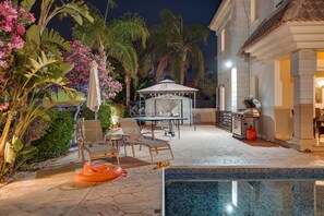 A pool area with lounge chairs, a barbecue setup, and a covered seating area. - Villa Hanna - 3 Bedroom Villa in Kapparis, Protaras (Protaras)
