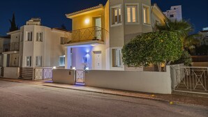 A two-story house with a balcony, a gated entrance, and a well-lit front door.