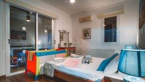 A bedroom with a bed, a window, a radiator, and a door leading to a balcony.