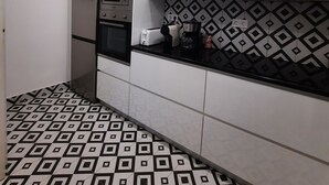 Eine moderne Küche mit weißen Schränken, einer Mikrowelle, einem Toaster und einer gefliesten Spritzschutzwand.