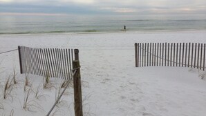 A beach with a wooden fence and a person in the distance.