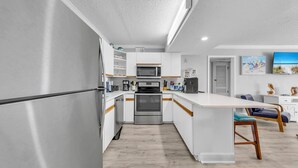 A modern kitchen with stainless steel appliances, white cabinetry, and a wooden island.