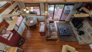 A spacious living area with a wooden floor, a leather sofa, a blue ottoman, a dining table with chairs, and a fireplace. - Eagle Point*VIEWS*Fireplace*Sleeps4*Resort*HIke* (Deep Gap)