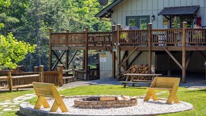 A wooden deck with a fire pit and seating area, surrounded by a stone border. - Eagle Point*VIEWS*Fireplace*Sleeps4*Resort*HIke* (Deep Gap)