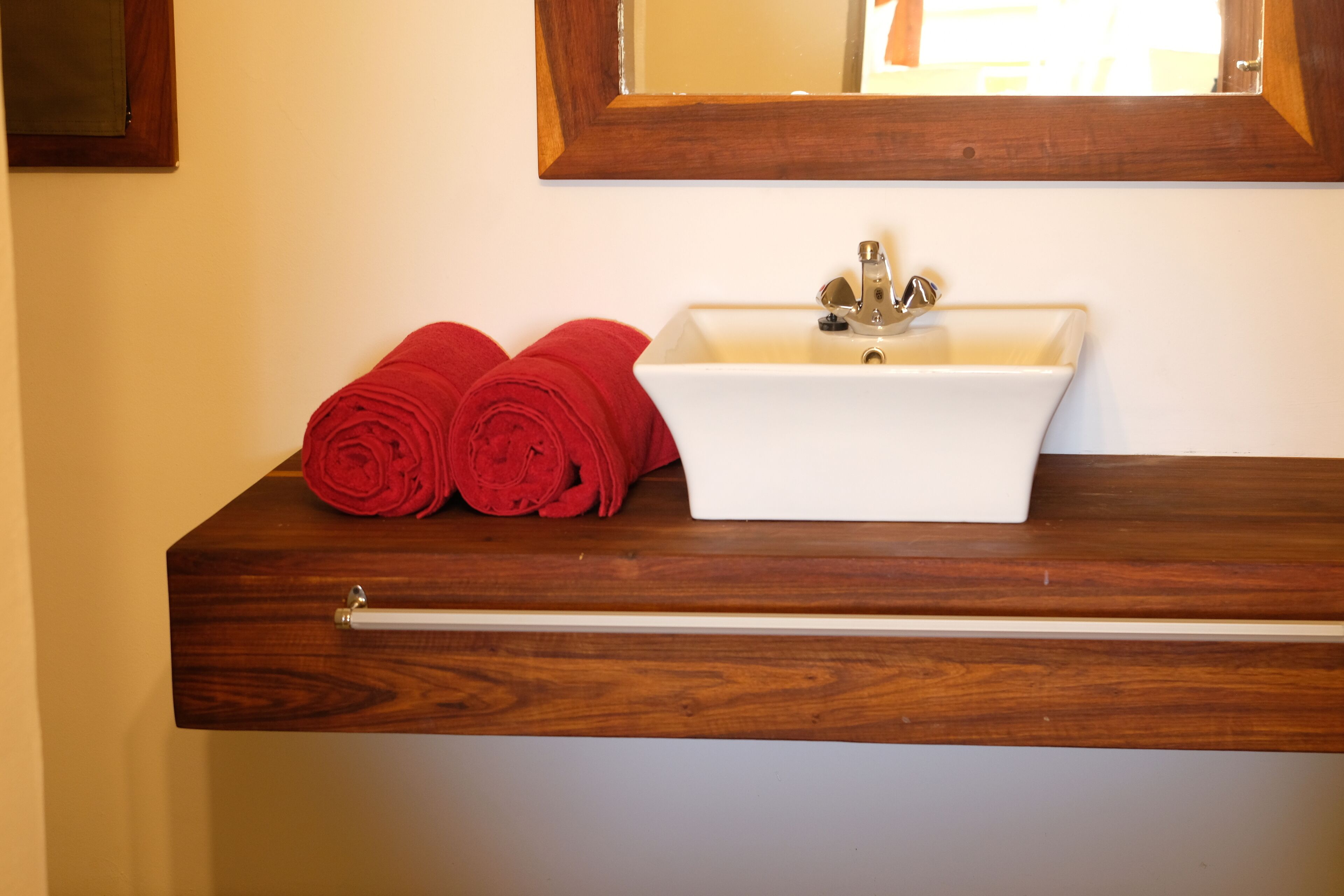 Un baño con lavamanos blanco, encimera de madera y espejo sobre el lavamanos.