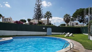 A swimming pool with a tiled deck, surrounded by a green fence, and palm trees in the background. - Selway Green Apartment, Wifi, Swimming Pool !New! (Quarteira)