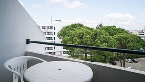 A balcony with a white table and chairs, a railing, and a view of a tree and buildings in the background. - Selway Green Apartment, Wifi, Swimming Pool !New! (Quarteira)
