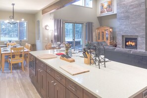 Een moderne keuken met een groot eiland, houten kastjes en een open haard.