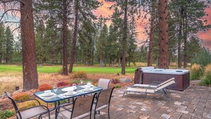 Une terrasse extérieure dotée d’un jacuzzi, de chaises longues et d’une table à manger pour six personnes.