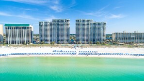 A beachfront hotel with multiple high-rise buildings, a sandy beach, and a clear blue sea. - Silver Beach 506 is a gorgeous Gulf Front 4 BR with free beach service - sleeps 8 by RedAwning (Destin)