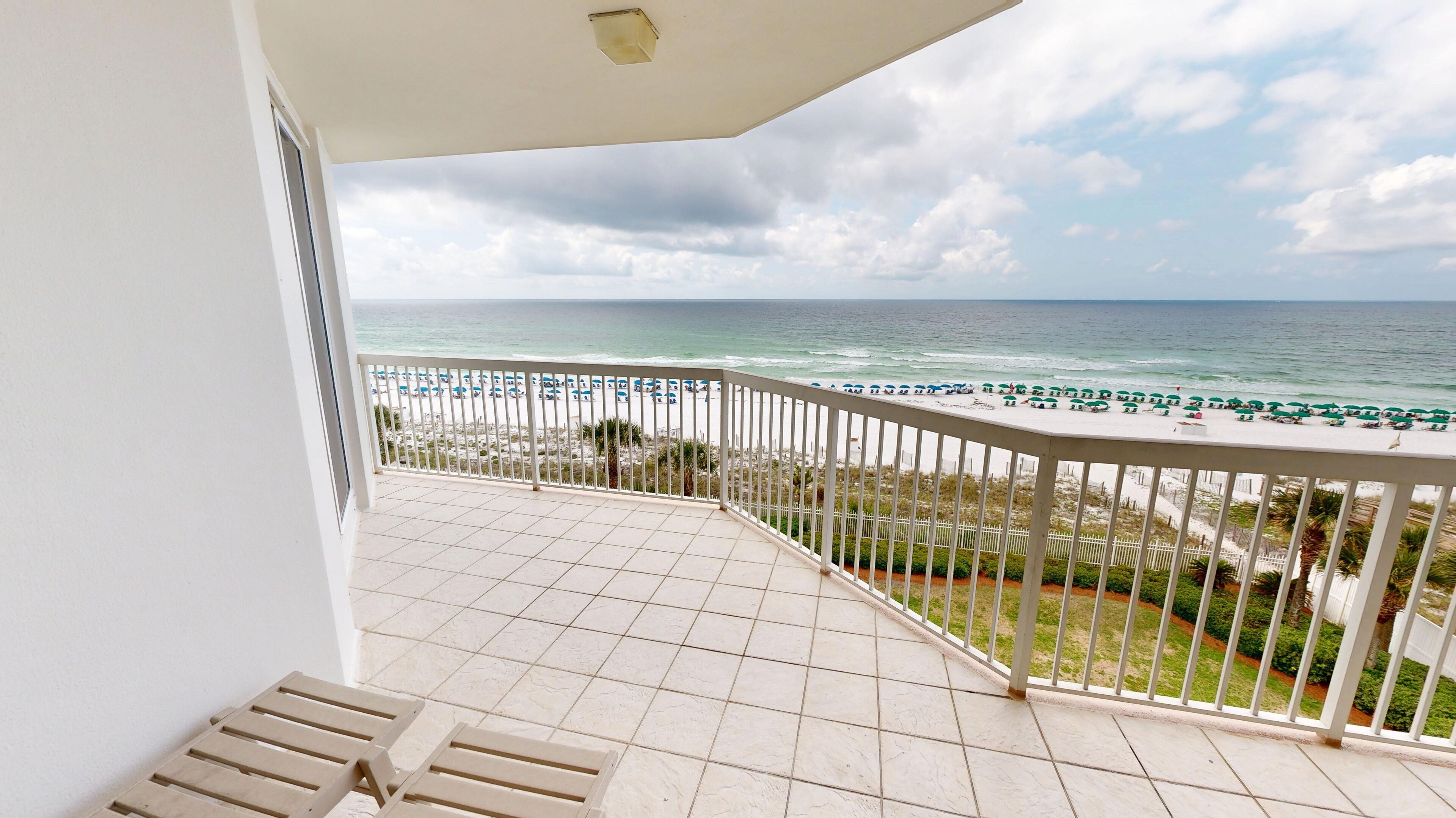 A balcony with a view of the beach and ocean.