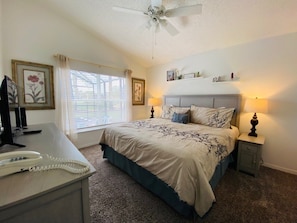 Relax in this serene bedroom with a large bed, bedside tables, and a ceiling fan above.