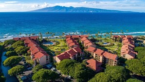 A resort with multiple buildings, a swimming pool, and a view of the ocean and mountains. - Papakea L-301  Direct Oceanfront Corner Unit with Panoramic Views (Lahaina)