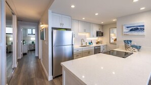 A modern kitchen with white cabinets, stainless steel appliances, and a large island. - Papakea L-301  Direct Oceanfront Corner Unit with Panoramic Views (Lahaina)