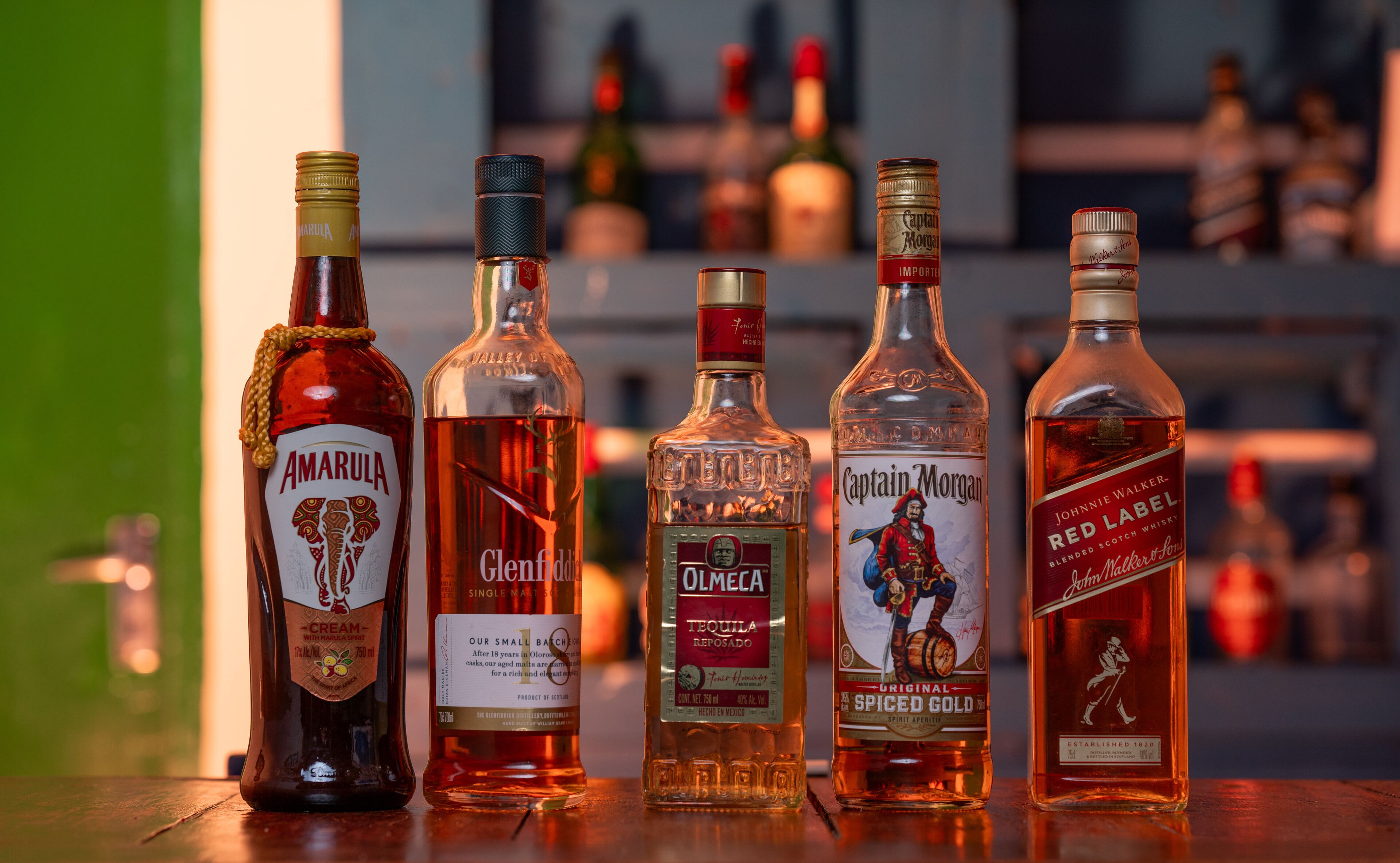 Cinq bouteilles d’alcool sont posées sur le comptoir d’un bar.