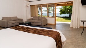 A bedroom with a large bed, two sofas, a coffee table, and a view of the outdoors. - Sunbird Chintheche Inn (Chintheche)