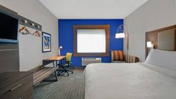 Una habitación de hotel con cama, escritorio, silla y ventana.