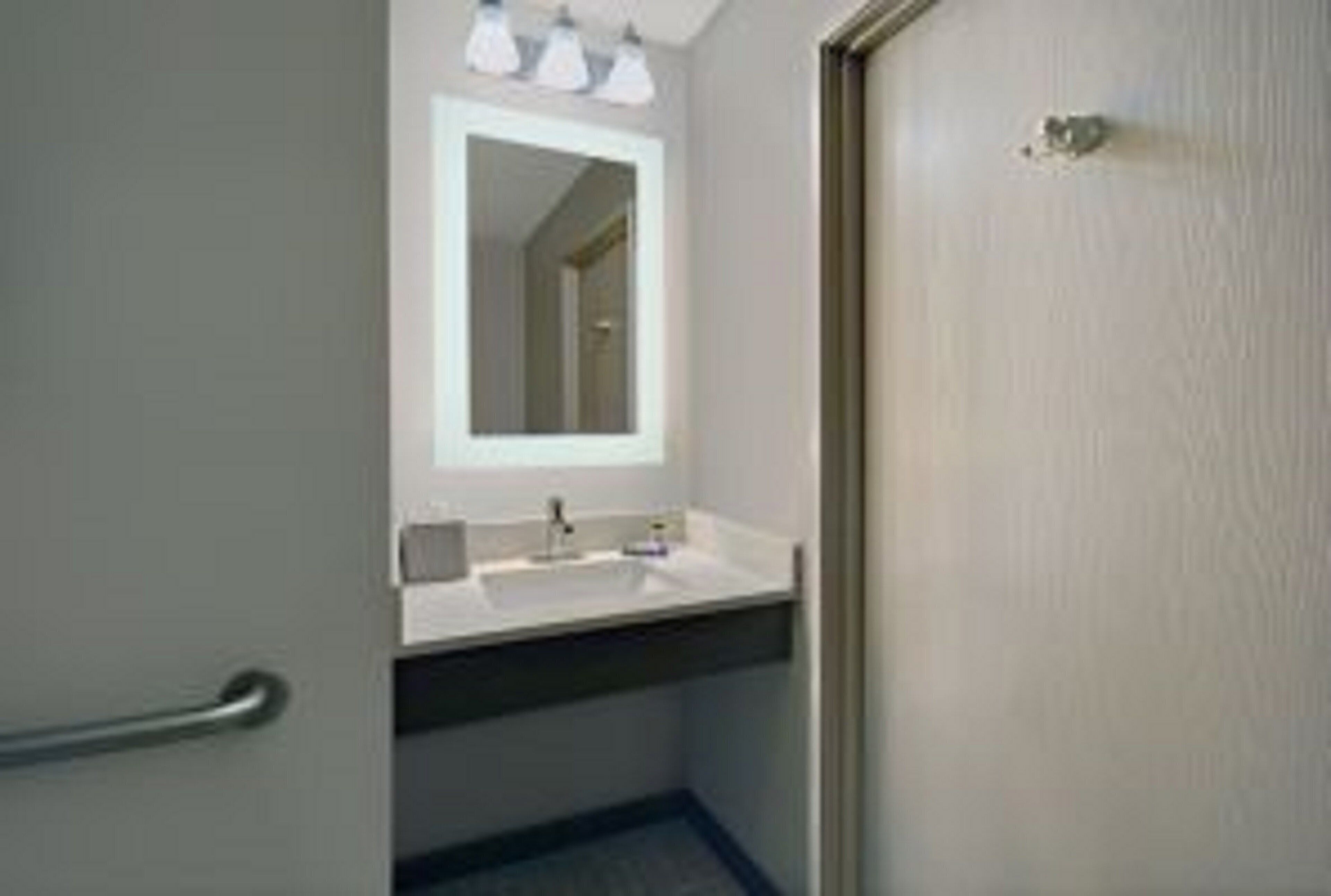 A bathroom with a white sink, a mirror, and three light fixtures above it.