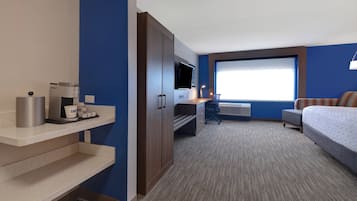 Una habitación de hotel con kitchenette, una cama, un escritorio y un ventanal grande.