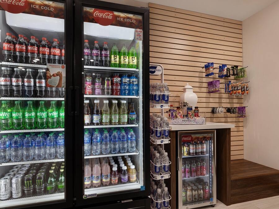 Un área de venta con bebidas Coca-Cola y Sprite refrigeradas, un dispensador de agua y una exhibición de aperitivos.