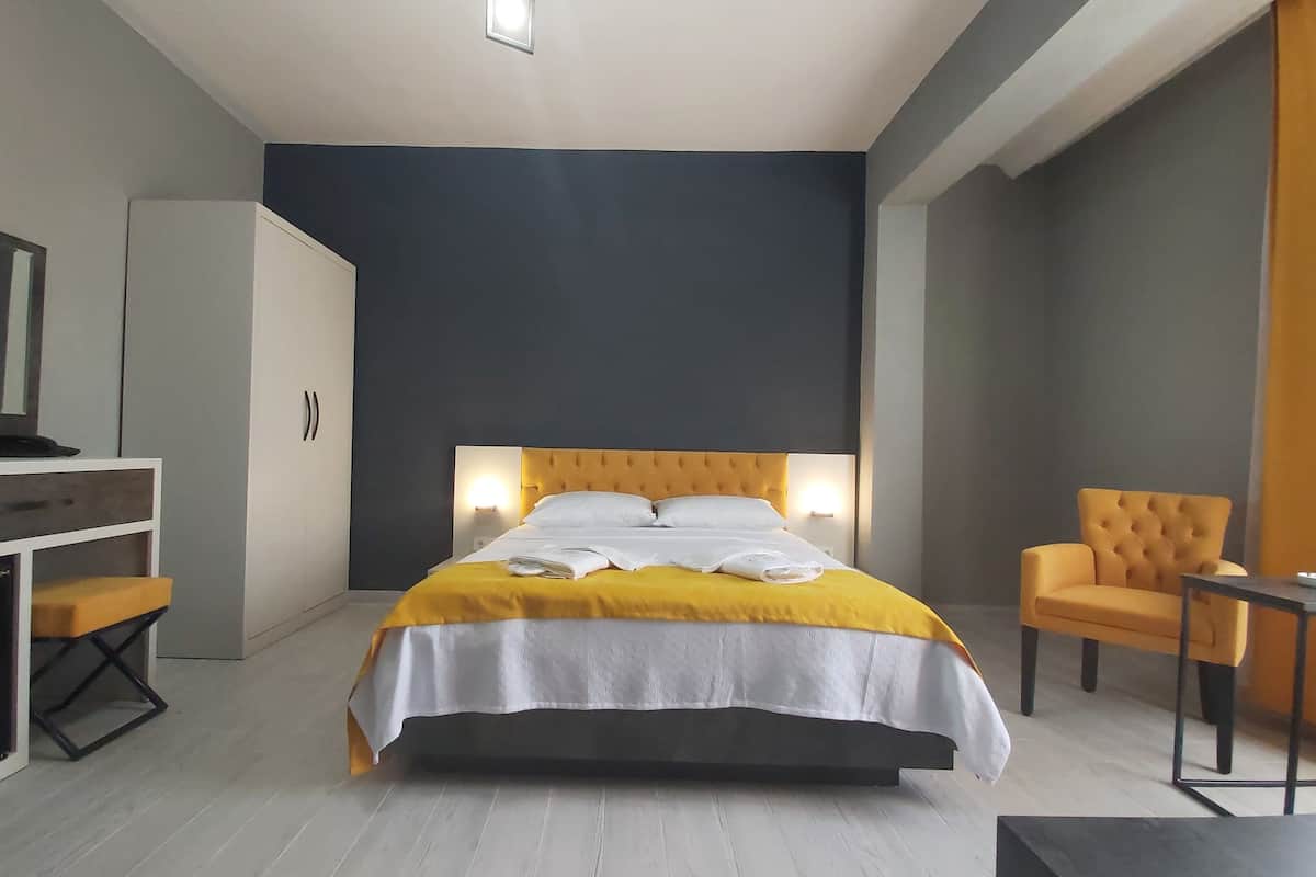 A modern hotel room with a bed, a desk, a chair, and a small table.