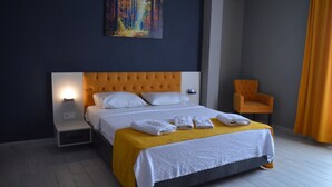 Una habitación de hotel con una cama grande, una mesita de noche, una silla y un cuadro en la pared.