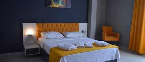 Quarto de hotel com uma cama grande, uma mesa de cabeceira, uma cadeira e um quadro na parede.