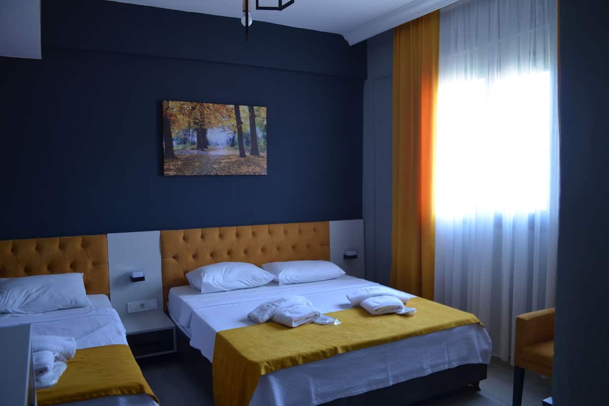 A hotel room with two beds, a painting on the wall, and a view of the outdoors through the window.