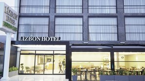 Un hotel con fachada moderna, amplias ventanas y un comedor visible con mesas y sillas.
