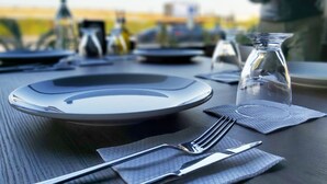 Una mesa servida para una comida, con platos, cubiertos y una jarra de vidrio.
