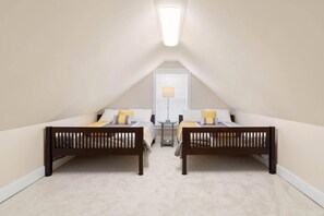 Een slaapkamer met twee bedden, een nachtkastje, een lamp en een raam met jaloezieën.