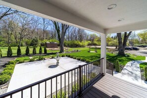 Une véranda abritée donnant sur une pelouse bien entretenue et un petit bâtiment situé au fond.