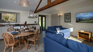 A modern kitchen with a dining table, chairs, and a blue sofa in a living area. - Grasmere Cottage with Stunning Views by LetMeStay (Ambleside)