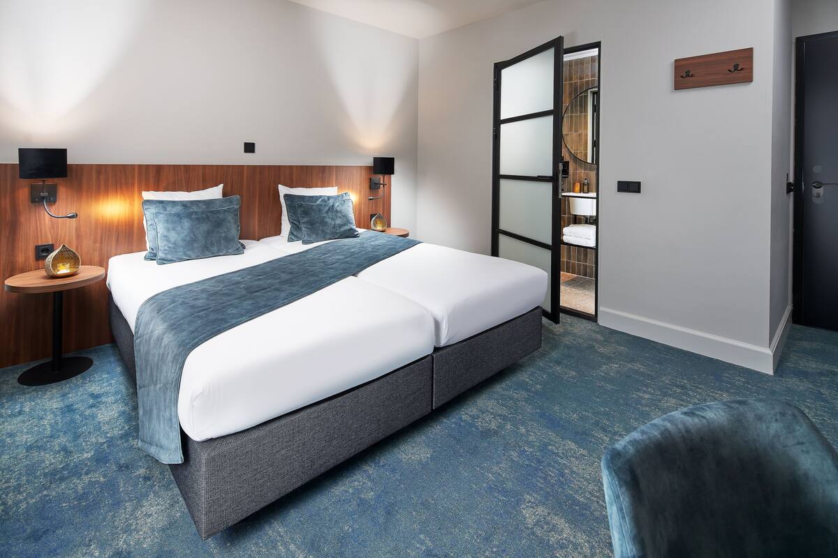 Una habitación de hotel con una cama grande, mesitas de noche, un televisor y un armario.