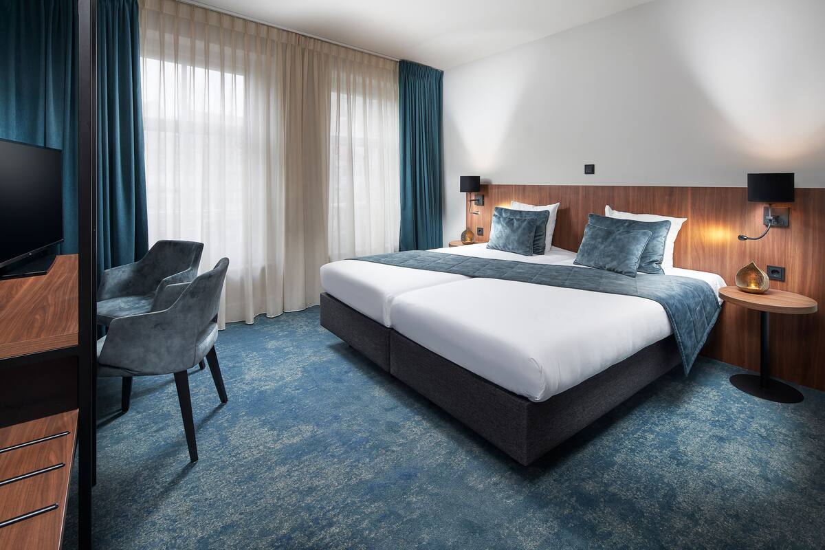 Una habitación de hotel con cama, escritorio, silla y televisor.