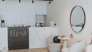 Uma área de recepção de hotel moderna com balcão de mármore, um tabuleiro de xadrez e assentos confortáveis.