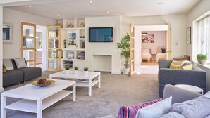 A modern living room with a grey sofa, white coffee table, and a bookshelf. - Finest House In Cheltenham ! (Cheltenham)