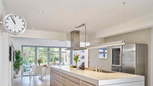 A modern kitchen with a large island, stainless steel appliances, and a view to the outdoors. - Finest House In Cheltenham ! (Cheltenham)
