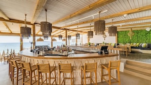 A bar area with wicker chairs, a bar counter, and a view of the ocean. - Skiathos Thalassa Philian Collection (Skiathos)