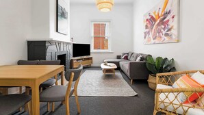 En moderne stue med pejs, sofa, spisebord og kunstværker.