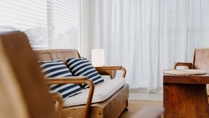 A cozy room with a wooden sofa, striped pillows, a small table, and a lamp. - Argyle Beach House by Book Jervis Bay (Vincentia)