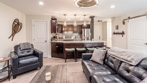 A modern kitchen with dark wood cabinets, a central island with bar stools, and pendant lighting. - Remodeled 1-Bdrm Ski-In/-Out Condo w/ Fireplace! (Steamboat Springs)