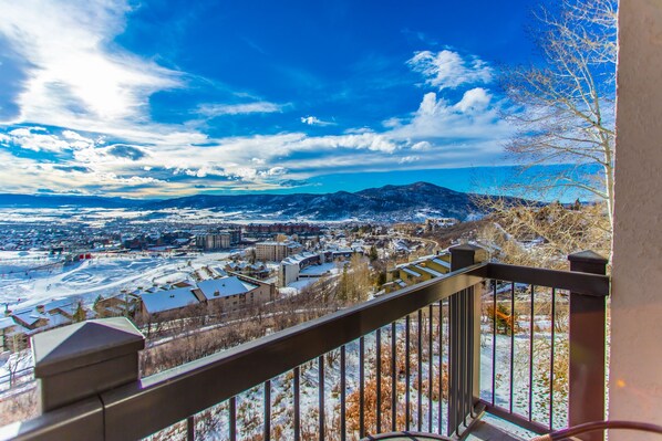 A balcony with a view of a snowy landscape, buildings, and mountains.