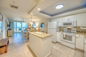 A modern kitchen with white cabinetry, a granite countertop, and stainless steel appliances.