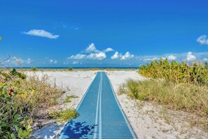 A pathway leading to the beach with a clear sky and ocean in the distance.