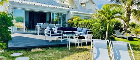 A modern house with a patio, outdoor furniture, and a view of the surrounding greenery.