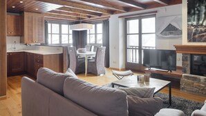 A modern living room with a sofa, a dining area with chairs, a kitchen with wooden cabinets, and a fireplace. - Val de Ruda Luxe 66 by FeelFree Rentals (Naut Aran)