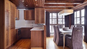 A modern kitchen with wooden cabinetry, a central island, and a dining area with a table and chairs. - Val de Ruda Luxe 66 by FeelFree Rentals (Naut Aran)