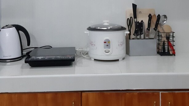 Una cucina con un bollitore, una pentola a cottura lenta e un portacoltelli sul bancone.