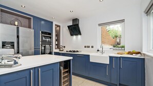 A modern kitchen with blue cabinets, stainless steel appliances, and a built-in wine cooler. - Clovelly House: Relaxed Family Coastal Home (Berwick-upon-Tweed)